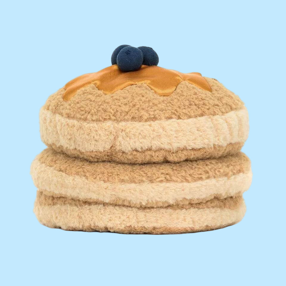 Stuffed toy resembling a layered dessert with caramel and blueberries on a white background