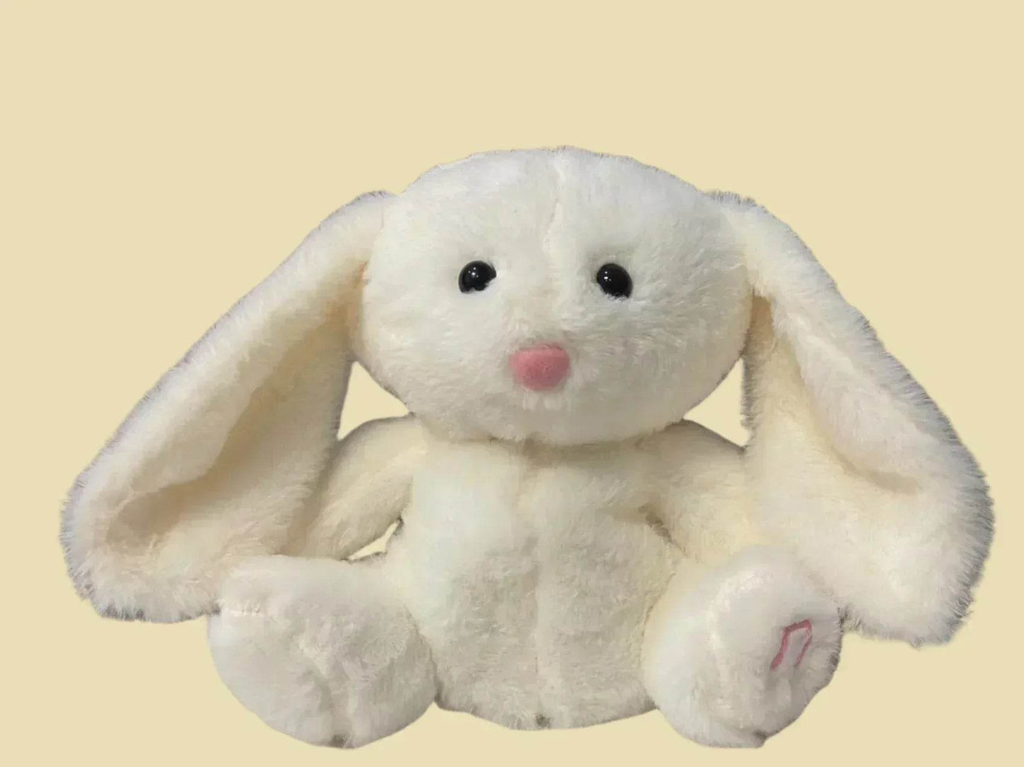 White plush bunny toy with a pink nose on a beige background