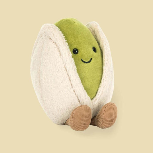 Plush toy shaped like a pistachio with a smiling face on a beige background
