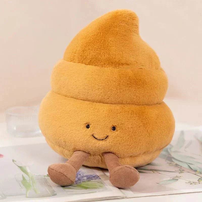 Plush toy shaped like a yellow poop emoji with a smiling face on a light background
